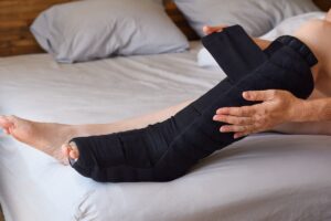 Woman sitting on bed putting on night compression wrap on lymphe